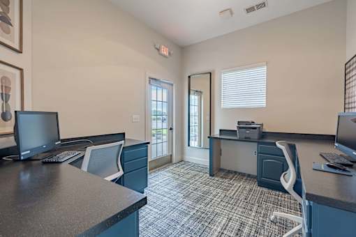 A room with a desk and chairs with a computer on it.