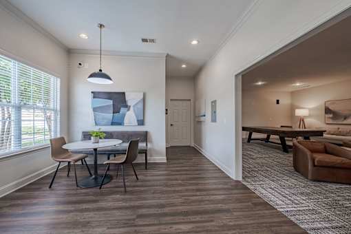 A modern dining room with a table set for two and a couch in the background.