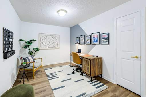 A room with a desk, chair, and pictures on the wall.