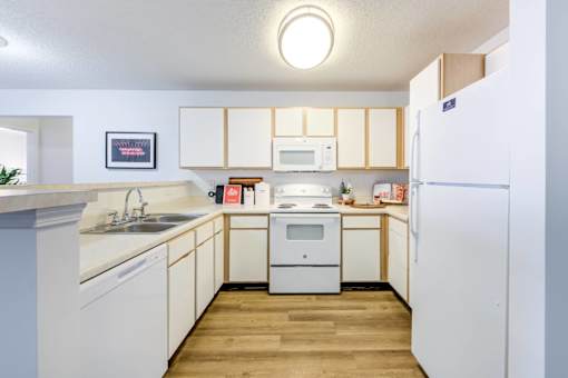 A kitchen with white cabinets and a white fridge.