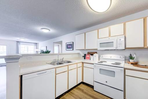 A white kitchen with wooden cabinets and a white stove.