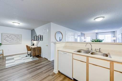 A kitchen with white cabinets and a wooden floor.