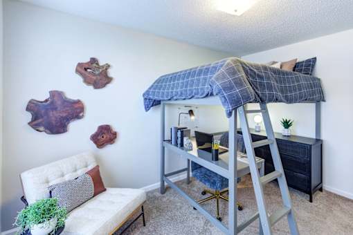A room with a bunk bed and a white chair.
