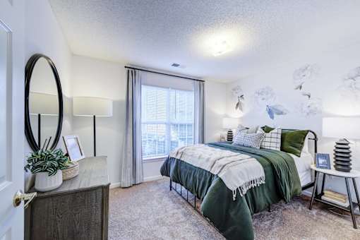 A bedroom with a bed, a dresser, and a mirror.