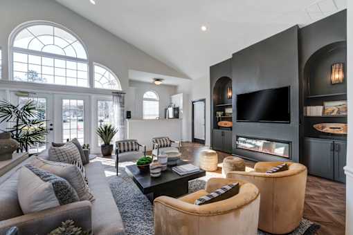 A modern living room with a grey sofa, a black coffee table, and a large window.