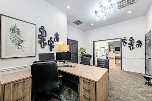 A modern office with a wooden desk and black chairs.
