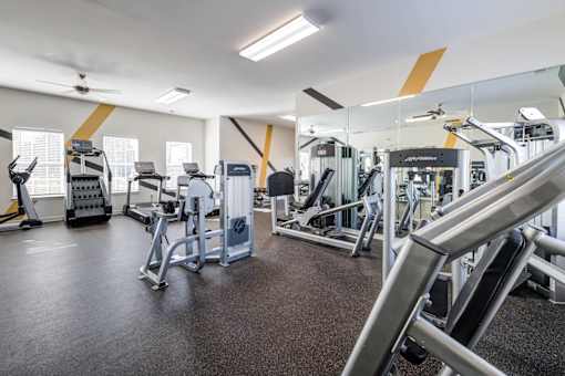 A gym with a variety of equipment including treadmills, weights, and exercise machines.