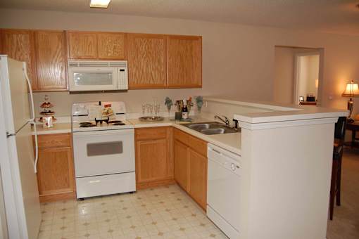 A kitchen with white appliances and wooden cabinets.