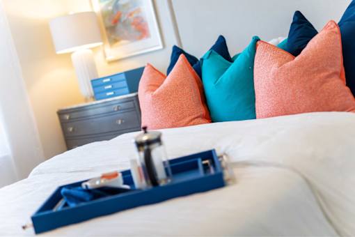 A bed with a blue tray on it and a lamp in the background.