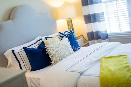 A bed with white sheets and blue and white pillows.