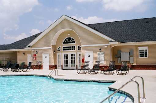 A pool in front of a house with a covered patio.