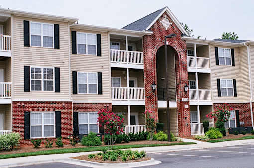 A brick building with a black trimmed window and a balcony.