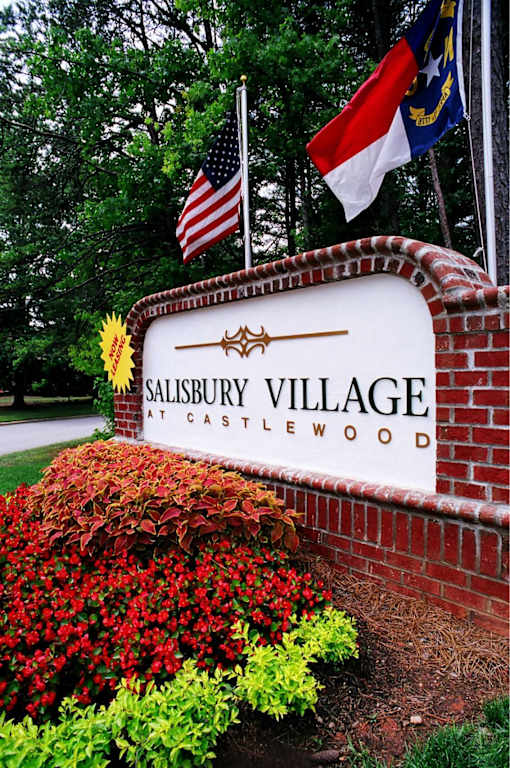 Salisbury Village at Castlewood sign with flags and flowers.