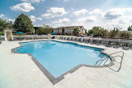 A large outdoor swimming pool with a diving board and a slide.