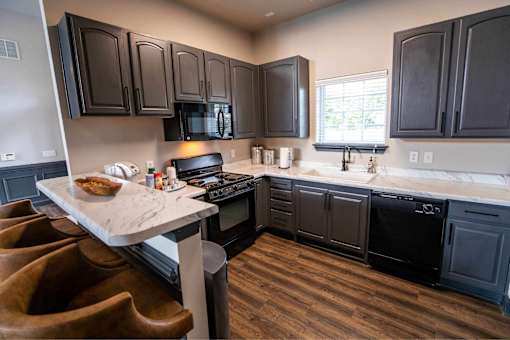 A kitchen with dark wood cabinets and a marble island.