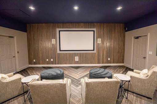 A room with a large screen and comfortable seating.