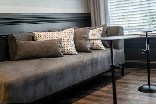 A grey couch with four pillows on it.