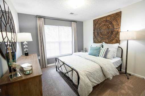 A bedroom with a large bed and a wooden dresser.