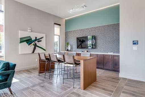 A room with a wooden table and chairs and a painting on the wall.