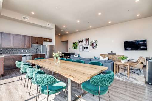 A modern open-concept living and dining area with a wooden table and green chairs.