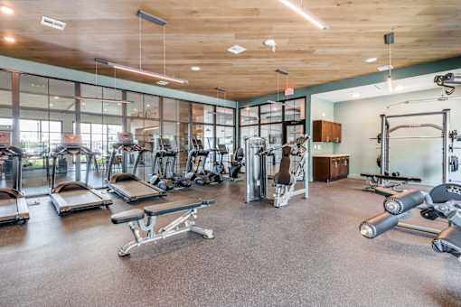 A gym with a variety of equipment including treadmills, weights, and exercise machines.