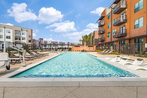 A long rectangular pool with a blue tiled edge sits between two apartment buildings.