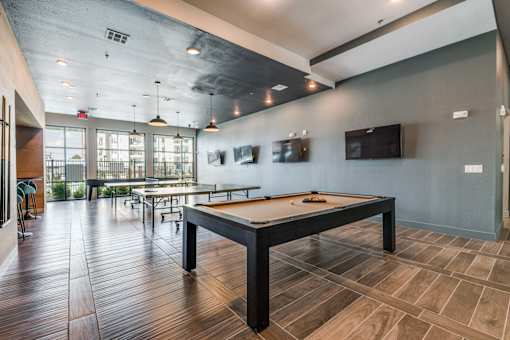 A room with a pool table and a bar area.