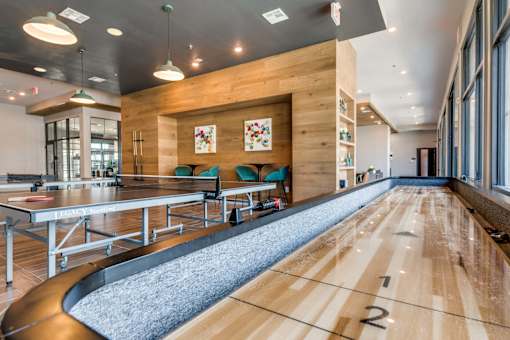 A room with a long table and chairs with a bowling alley in the middle.