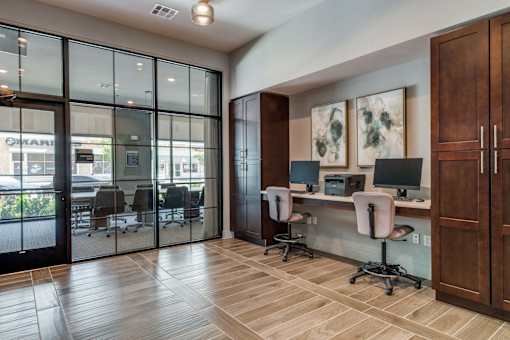 A room with a desk and chairs with a glass wall and a door.