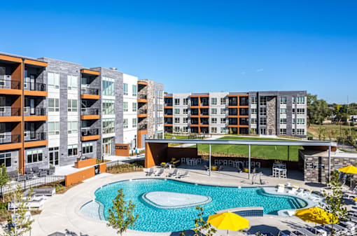 A large swimming pool is surrounded by apartment buildings.