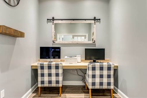 A desk with two chairs and a computer setup.