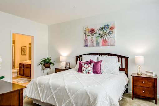 A bedroom with a large bed and a painting above it.