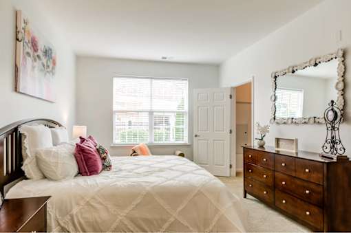 A bedroom with a large bed, a dresser, and a mirror.