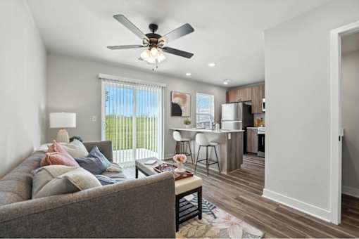 A living room with a grey couch and a ceiling fan.