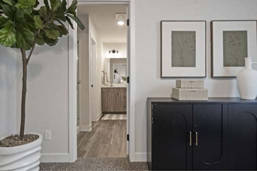 A black cabinet with a white vase on top and two framed pictures on the wall.