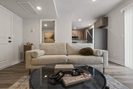 A modern living room with a beige couch and a glass coffee table.