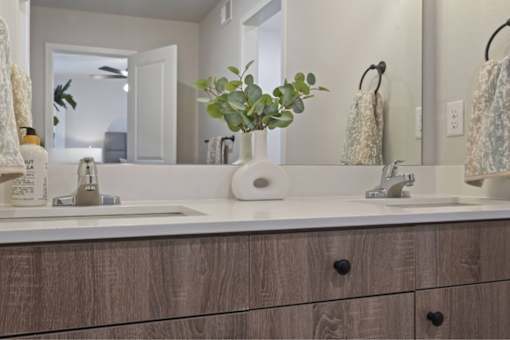 A bathroom with a white sink and a brown cabinet.
