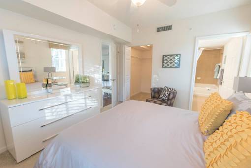 A bedroom with a large bed and a chair.