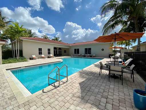 A pool with a blue tiled floor and a white building in the background.