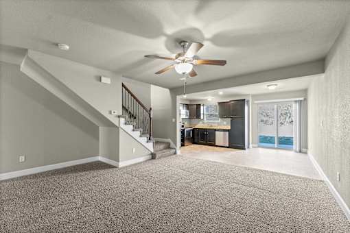 A spacious room with a staircase and a ceiling fan.
