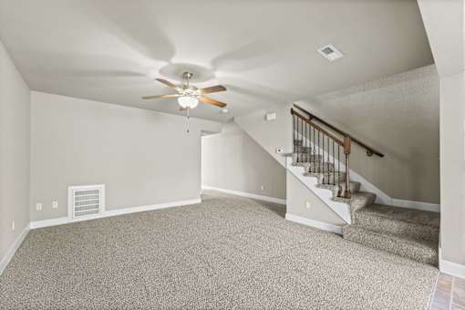 A room with a carpeted floor and a staircase.