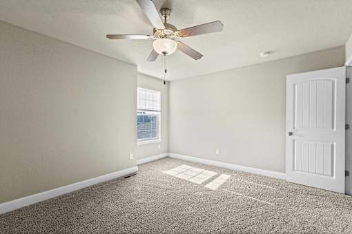 A room with a ceiling fan and a door.