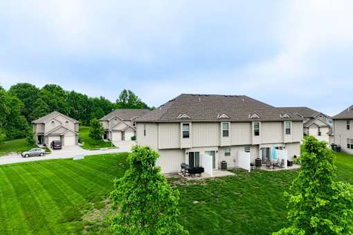 A large white house with a grey roof and a green lawn in front.
