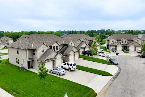 A row of houses with cars parked in front.
