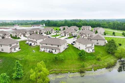 A bird's eye view of a residential area with houses and a pond.
