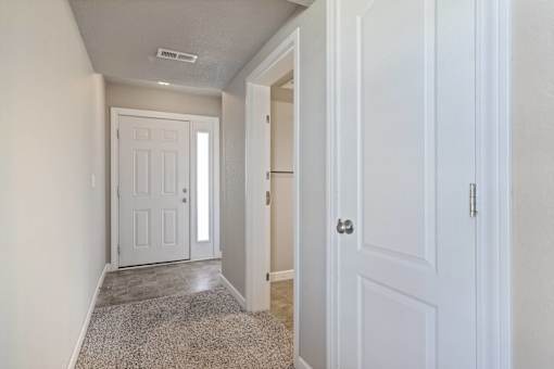 A hallway with a white door and a carpeted floor.