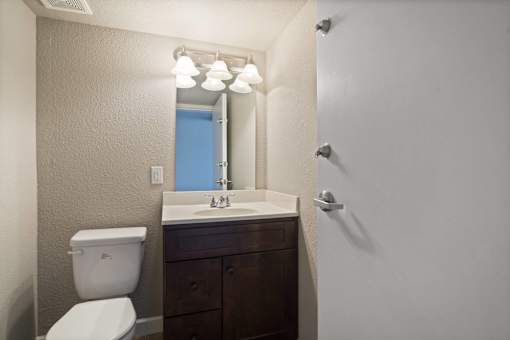 A bathroom with a toilet, sink, and mirror.