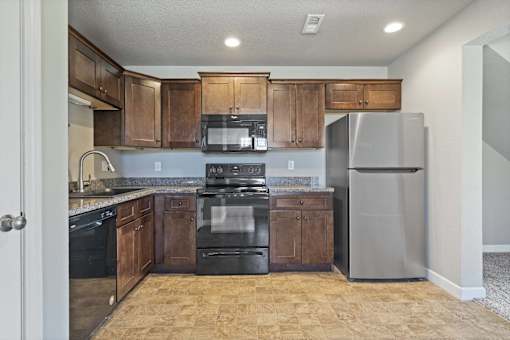 A kitchen with black appliances and wooden cabinets.