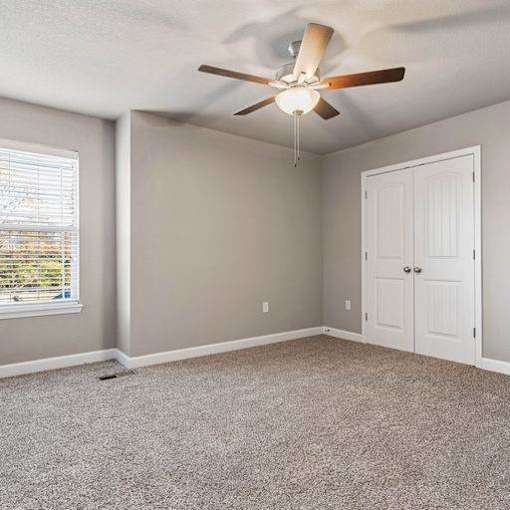 A room with a ceiling fan and a window with blinds.