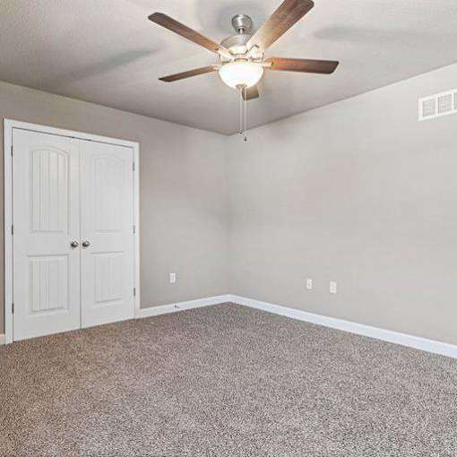 A room with a ceiling fan and a door.